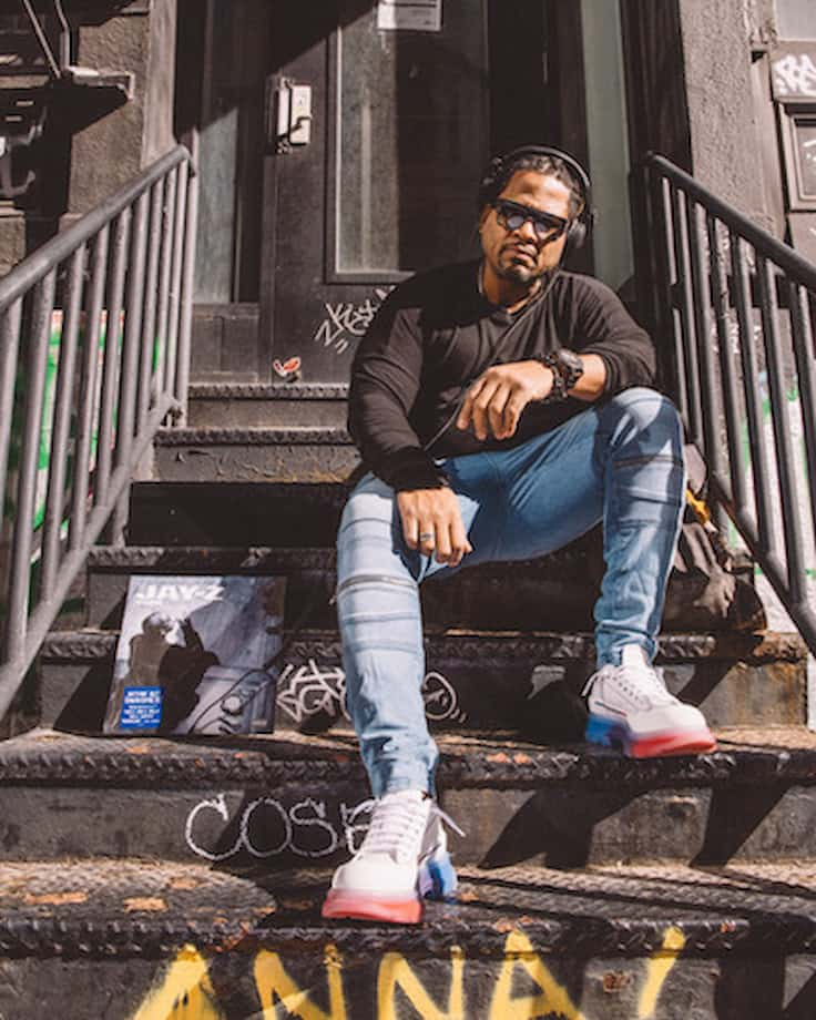 Kamau Preston sitting on stoop stairs with a Jay-Z record